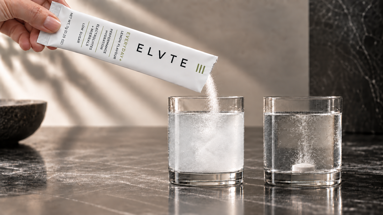 ELVTE powder poured into water beside a dissolving hydration tablet